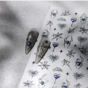 Macro detail of Gothic spider web nail stickers with purple gem heart on silver silk