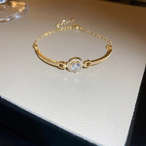 Close-up of gold bracelet with central round crystal and adjustable chain link detail
