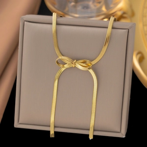 Detail of a gold snake bone chain necklace with a stylish bow knot on a jewelry box