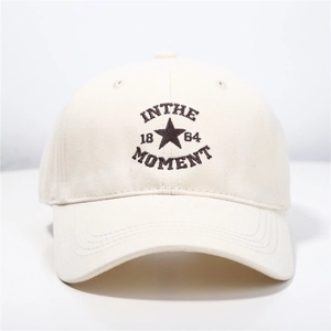 Detailed close-up of star embroidery and text on a beige cotton baseball cap