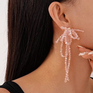 Close-up of elegant pink beaded bow earrings on model showing long tassel design