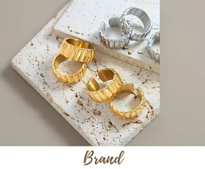 Detailed view of wide textured wavy rings in gold and silver finish on stone