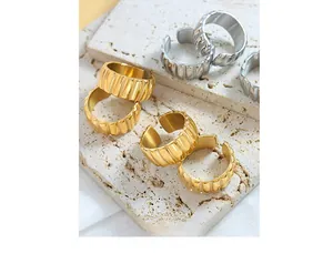 Detailed view of wide textured wavy rings in gold and silver finish on stone