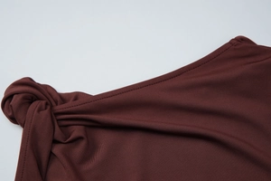 Detail of a dark brown knitted sleeveless top featuring a stylish front knot design