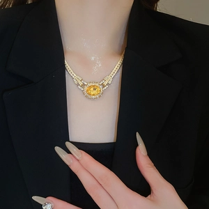 Close-up of a vintage gold necklace with a large oval amber stone on a black blazer