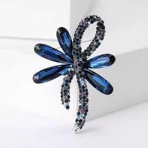 Detailed close-up of a dragonfly brooch with deep blue crystals and purple rhinestones