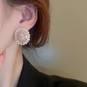 Detailed close-up of a floral crystal earring with a pink stone on a female model