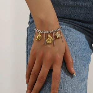 Close-up of ocean-style charm bracelet with starfish and shell pendants on a denim background