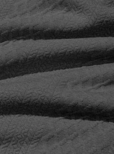 Close-up of dark grey jacquard fabric showing intricate geometric texture and thick fiber