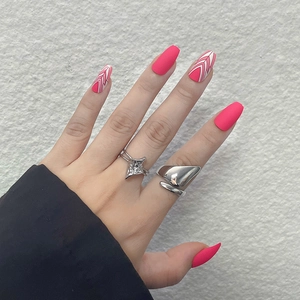 Short ballet pink matte press-on nails with white geometric arrow designs and silver rings