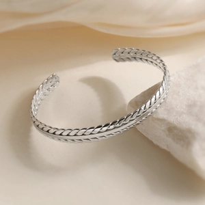 Adjustable silver wheat twist open cuff bracelet on elegant white stone and silk background