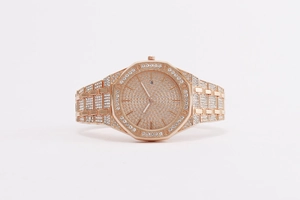 Macro detail of rose gold octagonal watch with iced-out crystals and date display