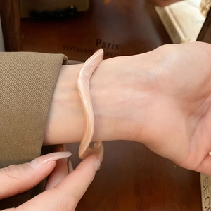 Detailed view of wave-shaped amber resin bangle on wrist with vintage aesthetic