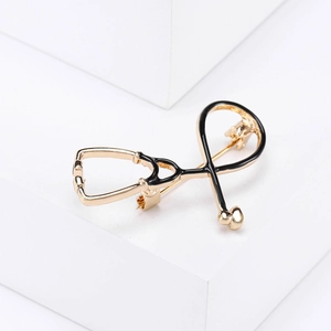 Macro shot of creative stethoscope brooch with gold metal base and black enamel finish