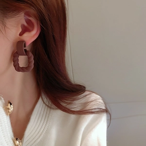 Detailed close-up of vintage brown geometric twist earrings worn by a model