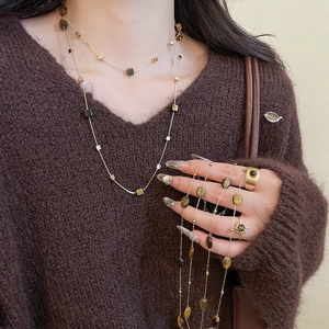 Close-up of double-layer Tiger Eye stone necklaces and matching sun-shaped gold rings