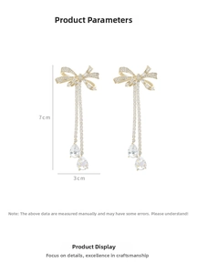Detail of gold bow earrings with micro-pave cubic zirconia and long tassels, size 7x3cm