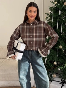 Detailed shot of brown plaid shirt featuring delicate white lace cuffs and button design