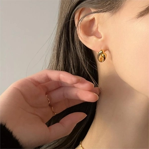 Close-up of minimalist gold twisted knot earrings worn by a model for a stylish look
