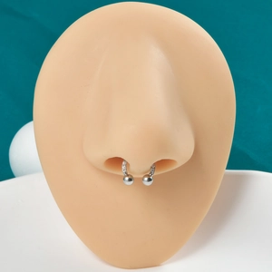 Macro view of silver septum ring with cubic zirconia stones on silicone nose model