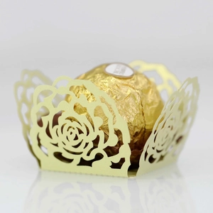 Macro view of laser-cut rose hollow cupcake wrappers in pale gold finish