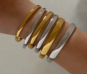 Close-up of stacked gold and silver minimalist titanium steel bangles on a woman's wrist