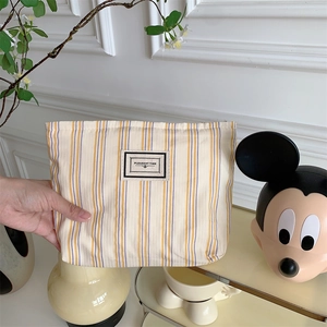 Close-up of a striped canvas toiletry bag featuring a Pleasant Time fabric label