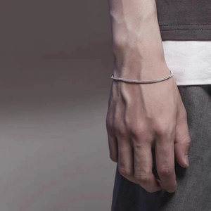 Detail of silver stainless steel chain bracelet with knot design on male model's wrist