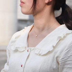 Close-up of minimalist gold S925 sterling silver lightning bolt pendant necklace on model