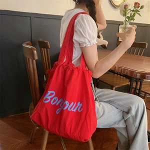 Detail of red drawstring canvas bag featuring blue Bonjour lettering in French style