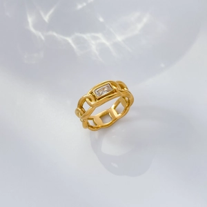Detail of gold chain-link ring featuring a rectangular emerald-cut zircon on white water-ripple