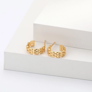 Close-up of golden braided twist hoop earrings on a minimalist white geometric stand