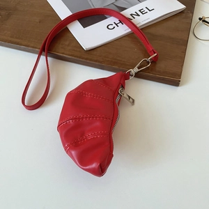 Vue détaillée du sac croissant en cuir PU rouge avec fermeture éclair argentée sur bois