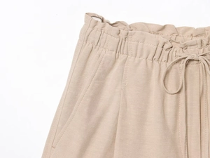 Detail of light khaki linen shorts featuring elastic drawstring waist and side pockets