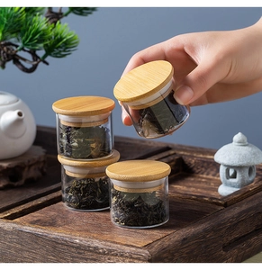 Detailed view of 4 small glass tea jars with bamboo lids for travel and storage
