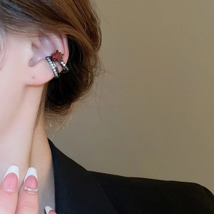 Détail de clips d'oreilles noirs avec gemme étoile rouge et zircons blancs