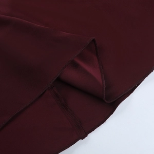 Detail of burgundy satin evening dress showing premium stitching and fabric texture