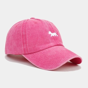 Dettaglio del cappello in cotone lavato rosa con ricamo bianco di un cagnolino