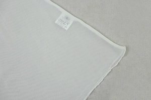 Macro shot of white translucent fabric texture and care instructions label on the dress