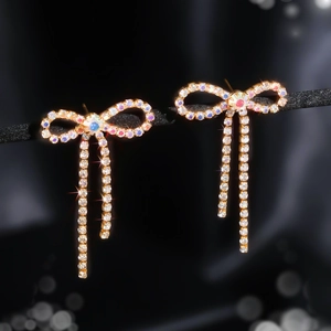 Close-up of sparkling bow tassel earrings with iridescent crystals and golden metal base