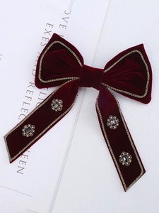 Close-up of velvet bow hair clip with gold bead edging and vintage gemstone accents