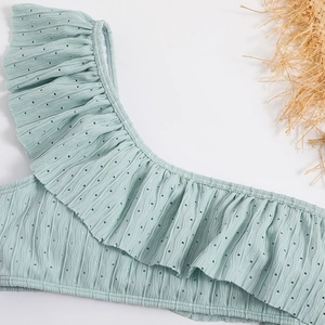 Macro shot of mint green ruffle swimsuit featuring textured knit and hollow-out details