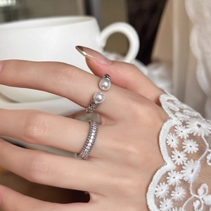 Close-up of elegant zircon paved ring and pearl open ring worn on a woman finger