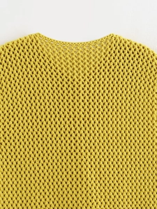 Dettaglio del gilet giallo all'uncinetto con intricati motivi floreali traforati