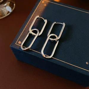Close-up of silver oval chain hoop earrings on a decorative dark blue jewelry box