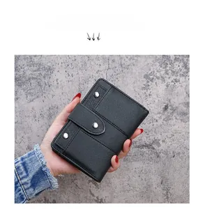 Close-up of black PU leather wallet with silver rivets and snap button held by hand
