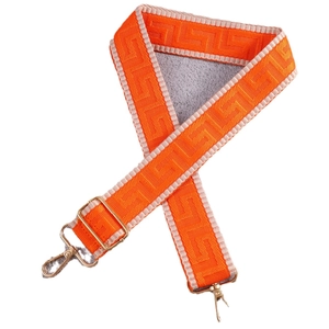 Ethnic style woven orange and beige wide shoulder strap with gold metal hooks on white background