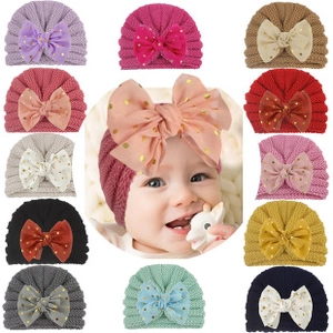 Detail of baby knitted hat featuring a large mesh bow with sparkling gold sequins