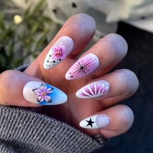 Detail of almond-shaped press-on nails with 3D floral accents and blue gradient design