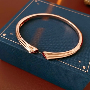 Close-up of rose gold open bangle with gourd design on a navy blue jewelry box